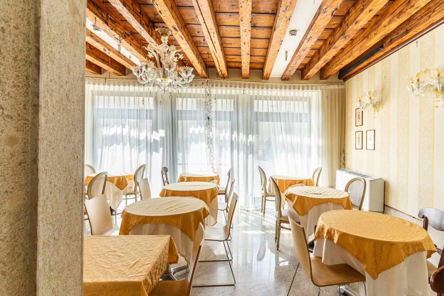 Sala da pranzo con pavimento in pietra e travi solaio in legno a vista a Venezia