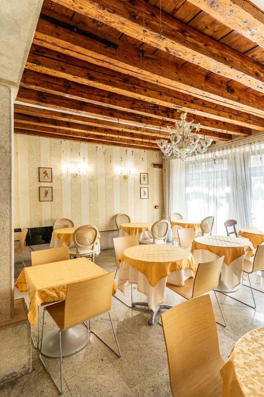 Sala da pranzo con pavimento in pietra e travi solaio in legno a vista a Venezia