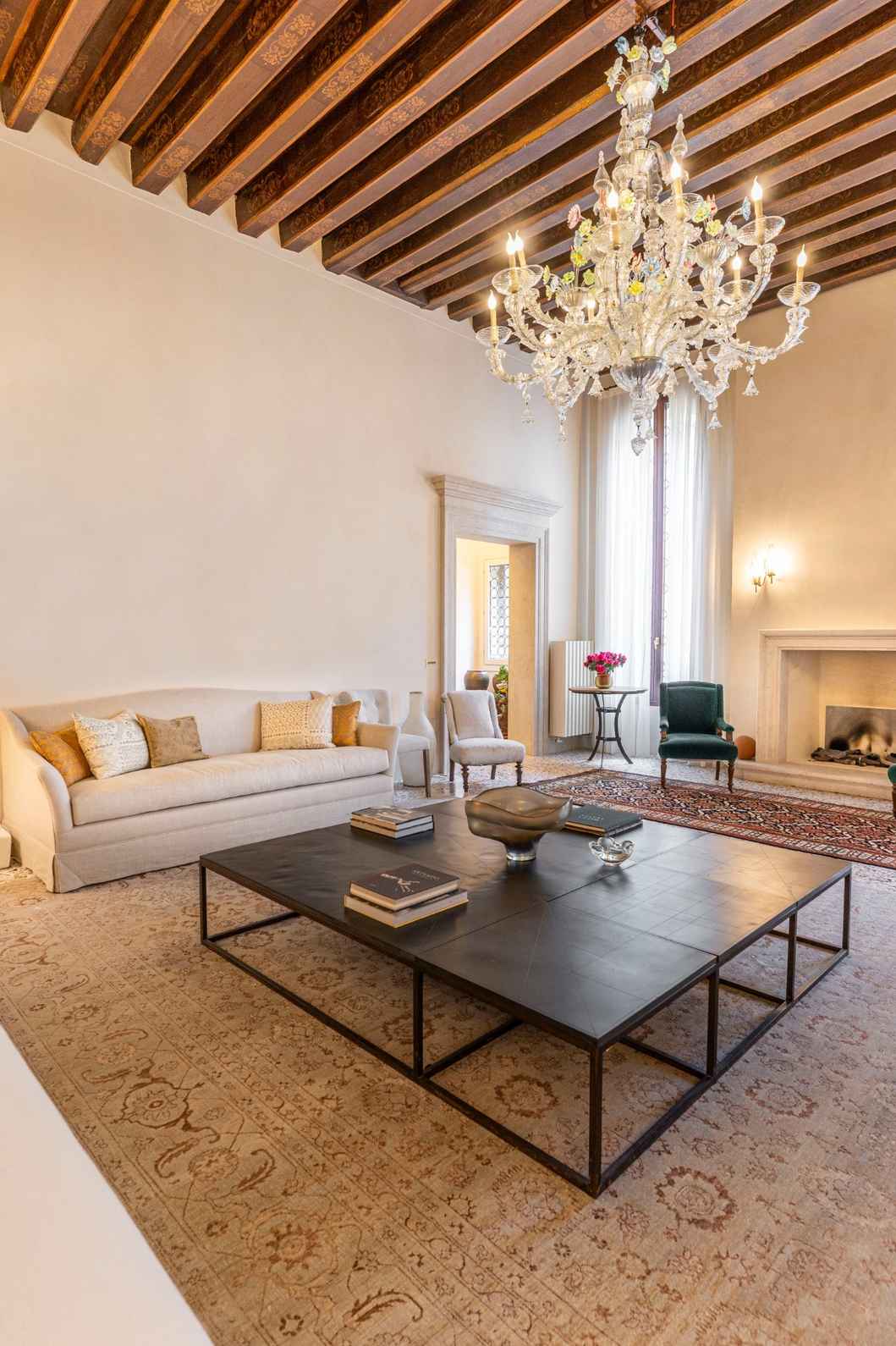 Salotto con travi a vista decorate e lampadario in vetro di Murano a Venezia